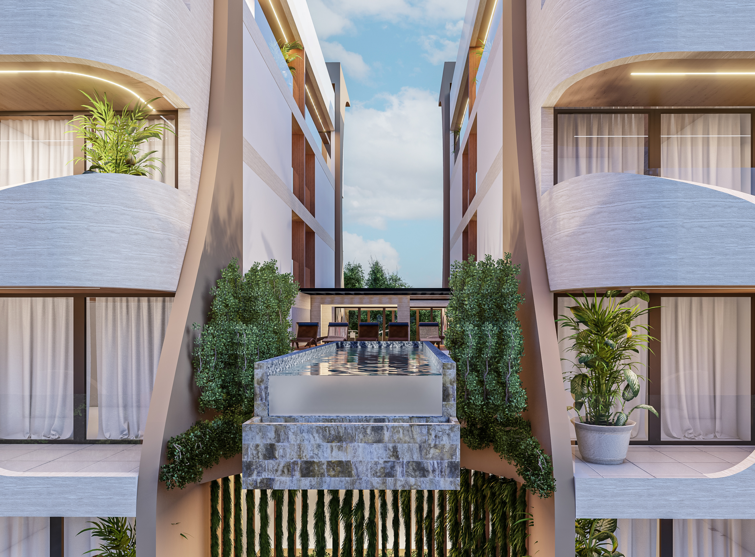 Symmetrical modern courtyard with a rectangular water fountain between two beige buildings, greenery along the sides and balconies above under a blue sky.