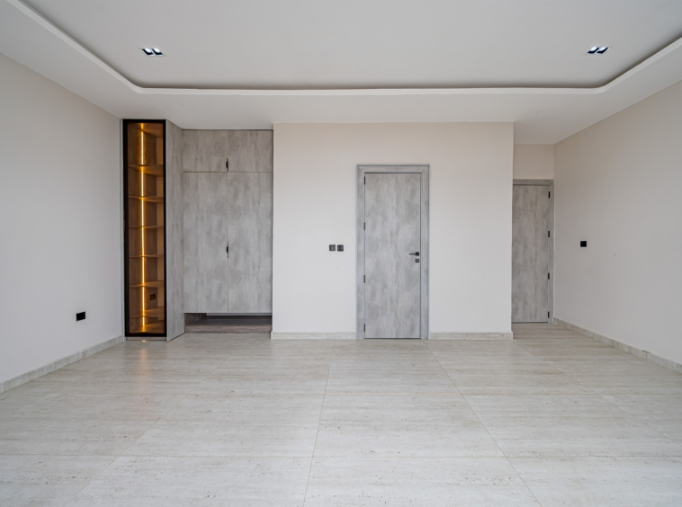 Empty modern room with light beige walls, light marble flooring, and gray built-in cabinets/doors.