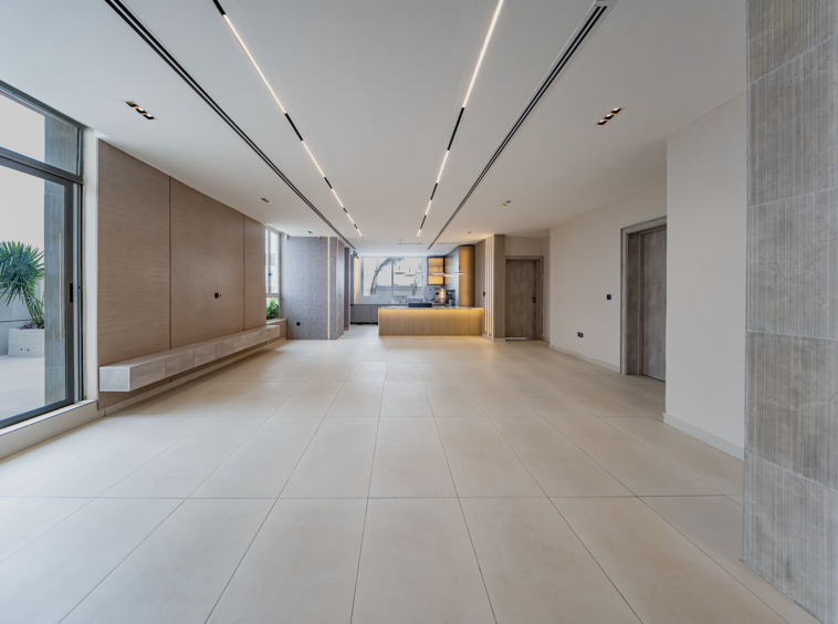 Bright modern lobby with a long reception desk, large windows, and neutral tile floor.